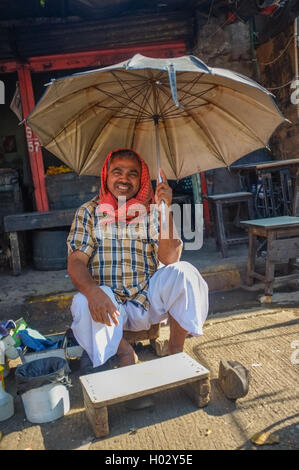 MUMBAI, Indien - 10. Januar 2015: indische Arbeiter sitzen unter einem Sonnenschirm auf Bürgersteig Stockfoto