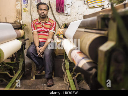 VARANASI, Indien - 21. Februar 2015: Arbeiter sitzt auf dem Stuhl neben Textilmaschine in kleinen Fabrik. Stockfoto