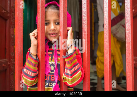 VARANASI, Indien - 20. Februar 2015: kleines Mädchen mit Schnupfen sieht durch geschlossenen Zaun eines kleinen Tempels. Stockfoto