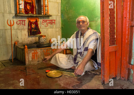 VARANASI, Indien - 20. Februar 2015: heiliger Mann sitzt am Boden in kleinen Tempel und wartet für Pilger. Stockfoto