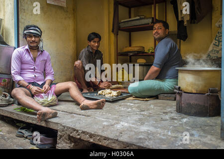 VARANASI, Indien - 20. Februar 2015: drei junge Erwachsene Männer sitzen auf Boden und Mittagessen in einfache Küche zubereiten. Stockfoto