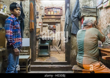 JODHPUR, Indien - 10. Februar 2015: junger Lehrling wartet auf Anweisungen, während Zimmermann arbeitet. Kinder werden als billige Chup verwendet. Stockfoto