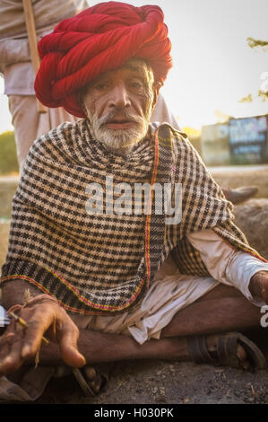GODWAR REGION, Indien - 14. Februar 2015: ältere Rabari Stammesangehörige mit roten Turban und Decke um die Schultern raucht Beedi. Stockfoto
