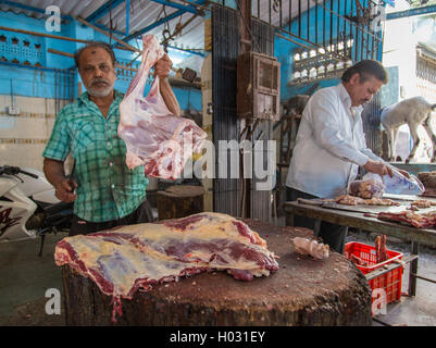 MUMBAI, Indien - 11. Januar 2015: Metzger zeigt Stück Hammelfleisch, während Kollege Fleisch neben ihm packt. Stockfoto