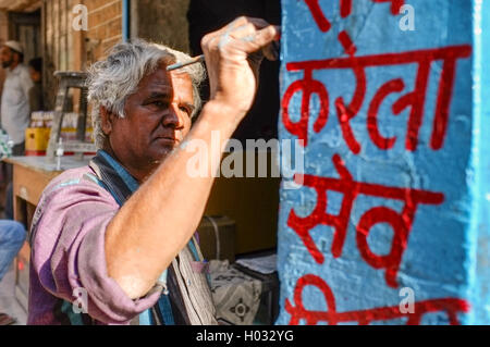 JODHPUR, Indien - 7. Februar 2015: Mann Malerei Zeichen auf Spalte. Indische Shop und Shop-Zeichen werden meist an Wänden, Säulen gemalt. Stockfoto