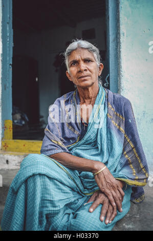 HAMPI, Indien - 31. Januar 2015: ältere indische Frau sitzt in Sari in Front des Hauses. Nachbearbeitet mit Getreide, Textur und colou Stockfoto