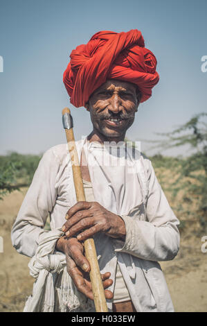 GODWAR REGION, Indien - 13. Februar 2015: Rabari Stammesangehörige hält traditionelle Axt auf Feld. Nachbearbeitet mit Korn, Textur und Stockfoto