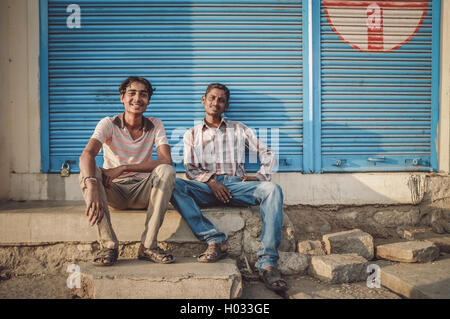 KAMALAPURAM, Indien - 02 Februar 2015: Lokale junge indische Männer sitzen vor Closed-Shop in einer Stadt in der Nähe von Hampi. Post-Prozess Stockfoto