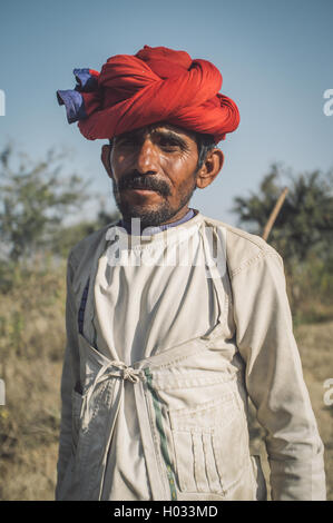 GODWAR REGION, Indien - 13. Februar 2015: Rabari Stammesangehörige hält traditionelle Axt auf Feld. Nachbearbeitet mit Korn, Textur und Stockfoto