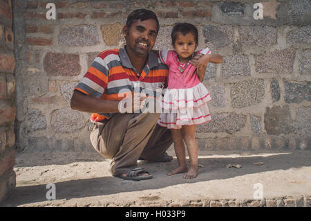 GODWAR REGION, Indien - 15. Februar 2015: glücklicher Vater hält Babymädchen unter der Schulter vor Haus. Kind trägt weiß und pin Stockfoto