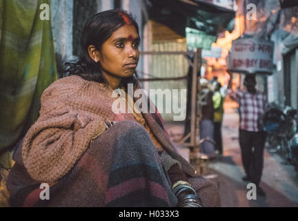 VARANASI, Indien - 25. Februar 2015: indische Obdachlose Frau sitzt in der Straße. Nachbearbeitet mit Getreide, Textur und Farbe effektiver Stockfoto