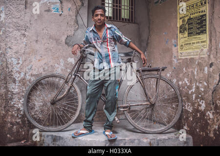 VARANASI, Indien - 25. Februar 2015: Indianerjunge steht neben traditionellen Fahrrad Teil in der Ecke der Straße. Nachbearbeitet mit Stockfoto