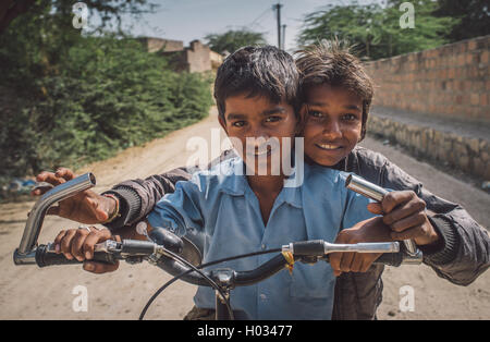 GODWAR REGION, Indien - 15. Februar 2015: zwei jungen auf einem Fahrrad in leere Dorfstraße. Nachbearbeitet mit Getreide, Textur und c Stockfoto