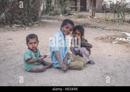 GODWAR, Indien - 12. Februar 2015: drei Kinder sitzen und spielen auf Schotter Dorfstraße eingeschliffen. Nachbearbeitet mit Korn, Textur Stockfoto