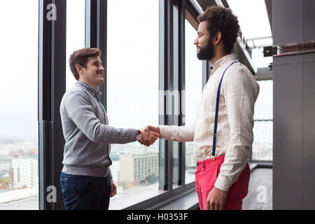 Zwei junge Geschäftsleute Händeschütteln im modernen Büro Halle. Stockfoto