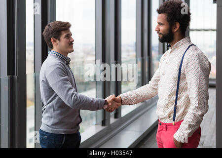 Zwei junge Geschäftsleute Händeschütteln im modernen Büro Halle. Stockfoto