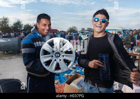 ZAGREB, Kroatien - 20. Oktober 2013: Roma Verkäufer Gebrauchtwagen-Felge und Whiskey-Paket auf Zagrebs Flohmarkt Hrelic halten. Stockfoto