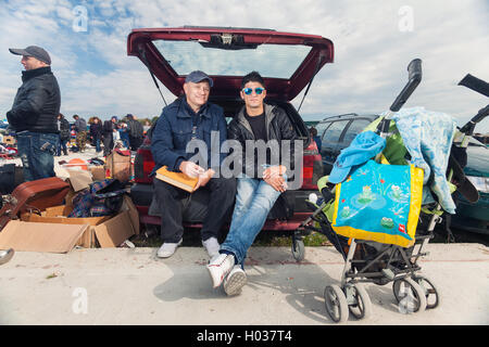 ZAGREB, Kroatien - 20. Oktober 2013: Junge Roma Mann sitzt in den Kofferraum eines Autos mit Verkäufer bei Zagrebs Flohmarkt Hrelic. Stockfoto