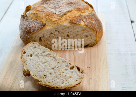 Eine Scheibe abschneiden von einem frisch gebackene hausgemachte Sauerteig Laib. Stockfoto