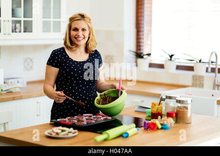 Schöne schwangere Frau Vorbereitung Muffins in Küche Stockfoto