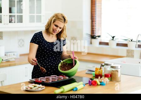 Schöne schwangere Frau Vorbereitung Muffins in Küche Stockfoto