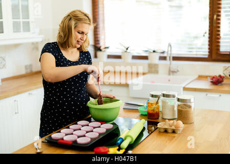 Schöne schwangere Frau Vorbereitung Muffins in Küche Stockfoto