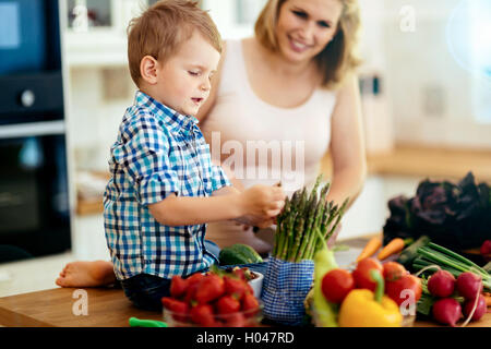 Mutter und Kind bereitet Mittagessen in Küche Stockfoto