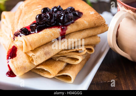 Hausgemachte Crepes mit Johannisbeeren Marmelade auf Frühjahr blühen Hintergrund in Dreiecke gefaltet Stockfoto