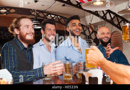 Man Gruppe In Bar halten Biergläser, stehen an der Theke bestellen Barkeeper, Mix Rennen fröhlich Freunde Stockfoto