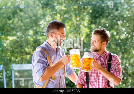 Männer in bayerischer Tracht Becher Bier halten Stockfoto