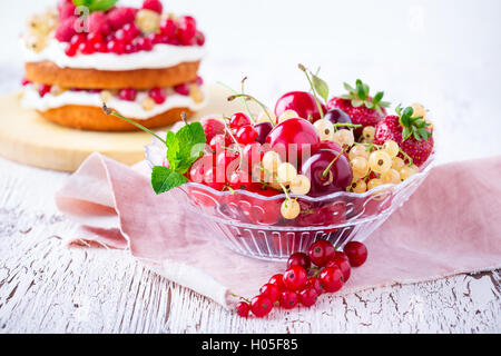 Frische Sommerbeeren und Früchte in Glasschüssel auf rustikalen Holztisch, selektiven Fokus Stockfoto