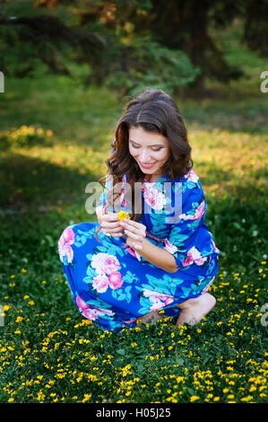 schöne Frau, die gelben Blumen auf einer Wiese zu pflücken Stockfoto