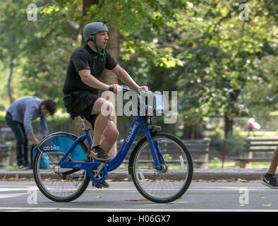 Ein Mann reitet einen citibike im Central Park das Tragen eines Helmes. Stockfoto