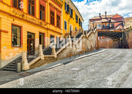 Gepflasterte Straße führt unter der Brücke liegt, ein Wahrzeichen der alten Stadt von Sibiu, Rumänien Stockfoto