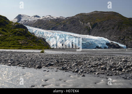 Ein schlammiger Strom fließt über das Bild mit Portage Glacier im Hintergrund. Stockfoto