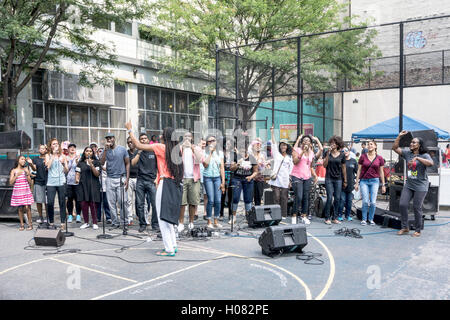 Mitglieder des Times Square Kirche Gospel Chor singen Herzen heraus in Gratis-Konzert am Spielplatz des lokalen berufsbildende Schule Stockfoto