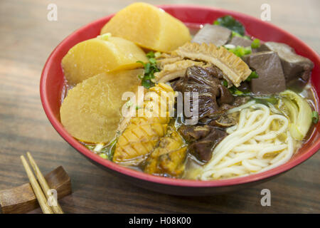 Chinesische Schüssel Nudeln mit Tintenfisch, getrocknetes Schweineblut und Radieschen auf dem Tisch Stockfoto