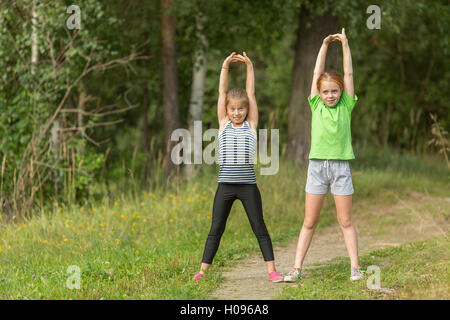 Zwei kleine Mädchen führen Sie gymnastische Übungen im Freien. Stockfoto