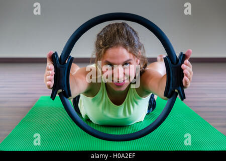 Eine junge Frau Training Pilates ist, Halten und schauen durch den Ring, Deutschland Stockfoto