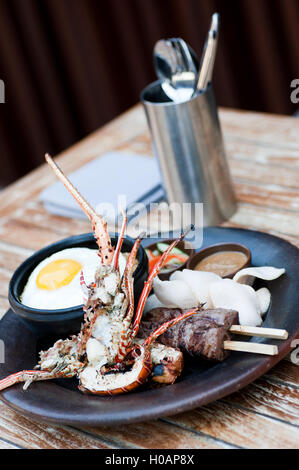 Gegrillter Hummer mit Spießen und Eiern auf schwarze Platte im restaurant Stockfoto