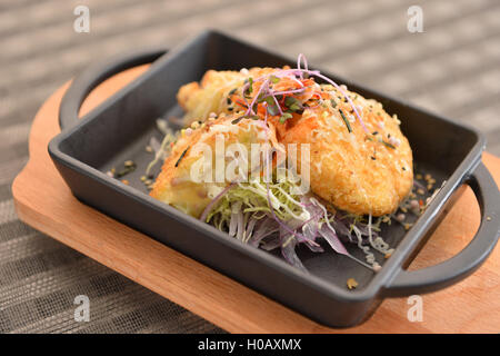 Reiskuchen mit Salat auf schwarzen Eintopf auf Schneidebrett Stockfoto