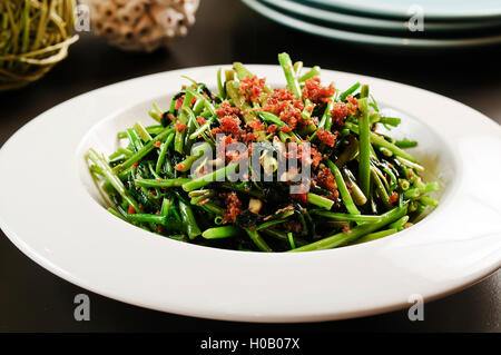 Gebratenes Gemüse der Trichterwinde oder Rau Muong auf weißen Teller in Vietnam Stockfoto