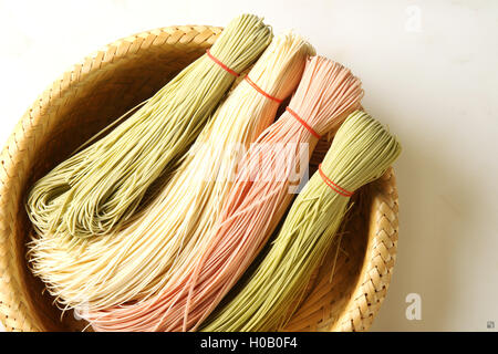Bunte chinesische Spaghetti auf Bambuskorb in weißem Hintergrund Stockfoto