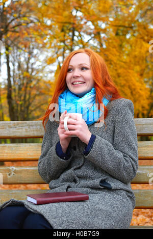Mädchen mit Tasse warme Hände in gelben Stadtpark Herbstsaison Stockfoto