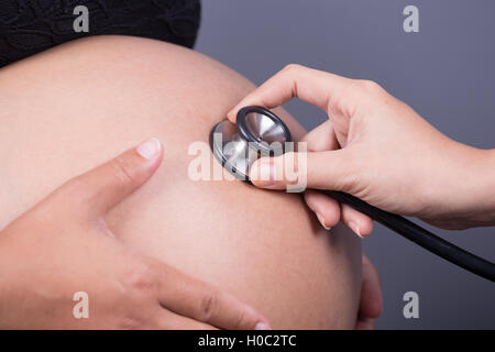 Nahaufnahme der Bauch einer schwangeren Frau, die mit einem Stethoskop untersucht Stockfoto