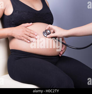 Nahaufnahme der Bauch einer schwangeren Frau, die mit einem Stethoskop untersucht Stockfoto