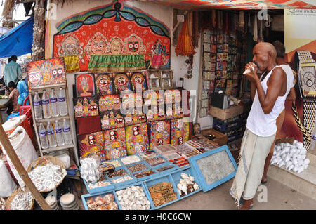 Puri, Odisha, Indien - 3. Juli 2011: Memento von Lord Jagannath, Balbhadra und Subhadra auf dem Display und einen alten Kunden im Shop. Stockfoto