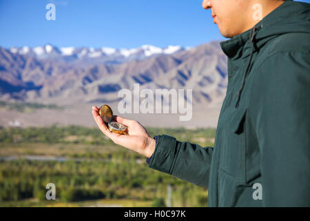 Junge Reisende auf der Suche bei Compass im Himalaya Bergblick Hintergrund Stockfoto