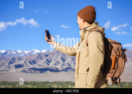 Junge asiatische Wanderer mit einem Smartphone auf Berggipfel in Leh, Ladakh, Indien Stockfoto