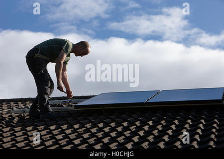 Mann, die Installation auf dem Dach Solarpanel Array in einer inländischen Solar-Panel-Installation im Vereinigten Königreich Stockfoto